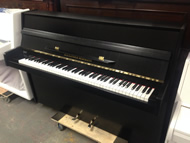 Alexander Herrmann Modern Black satin upright piano.