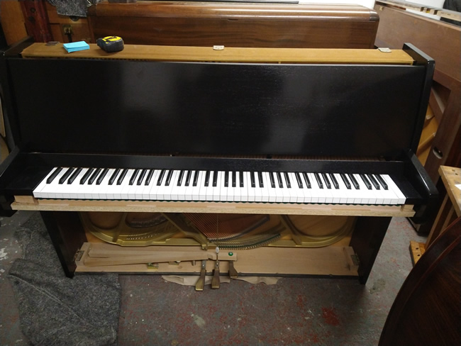 Kemble black gloss upright pianos.