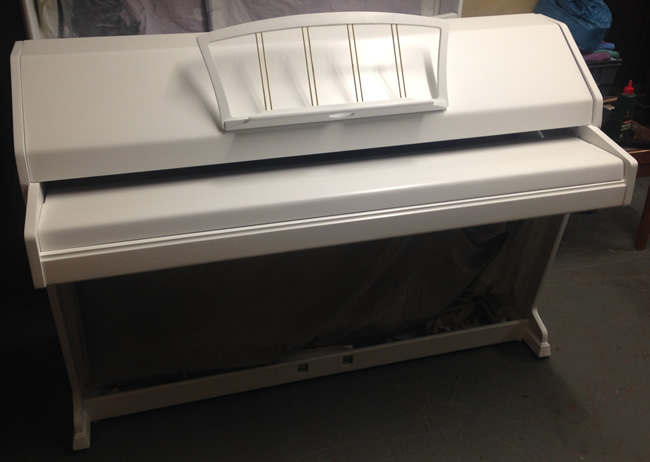 White satin Eavestaff piano being re-assemled.