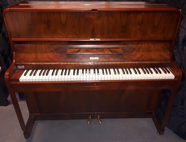 Squire upright piano in a Walnut satin cabinet.